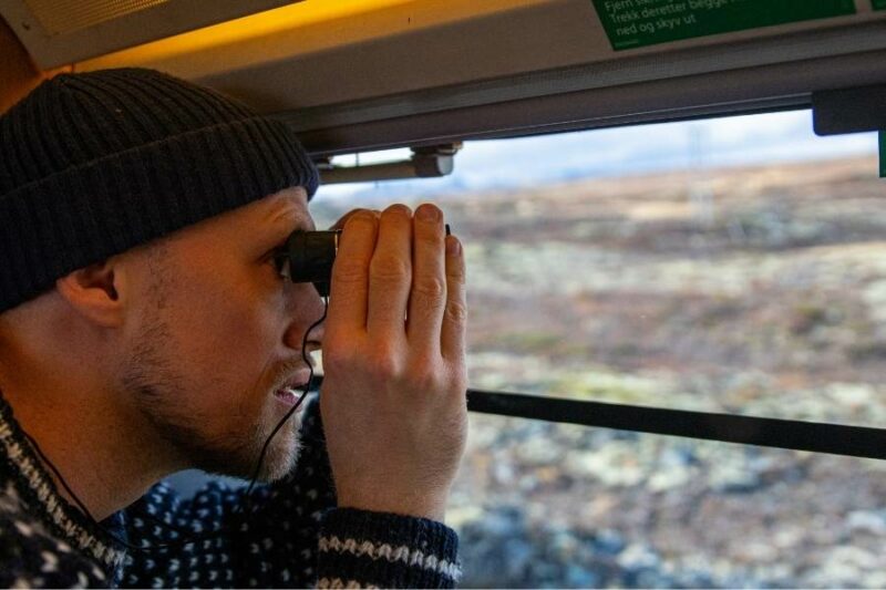 Man kijkt met verrekijker uit trein Noorwegen
